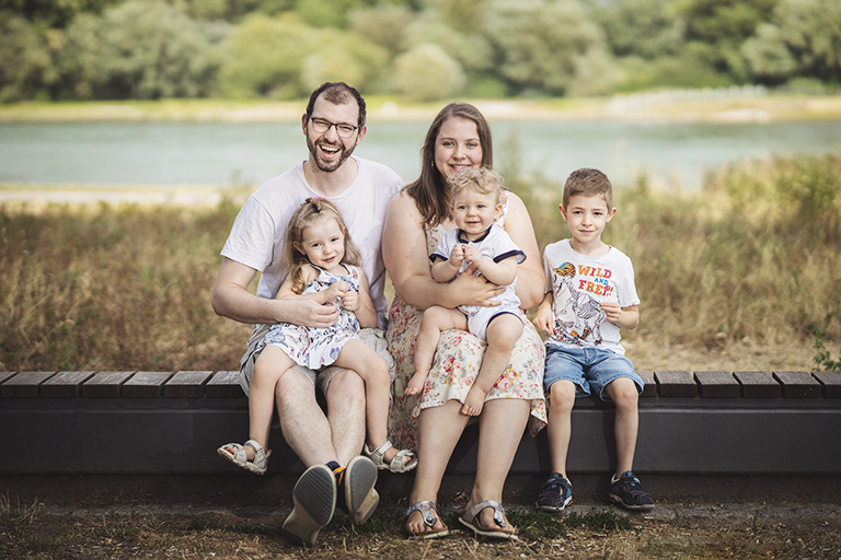 Familienfoto am Rhein in Germersheim, Eltern und drei Kinder sitzen auf Bank